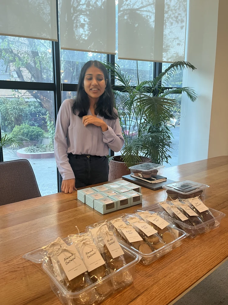 Kajal Jain standing beside a table of packaged homemade cookies